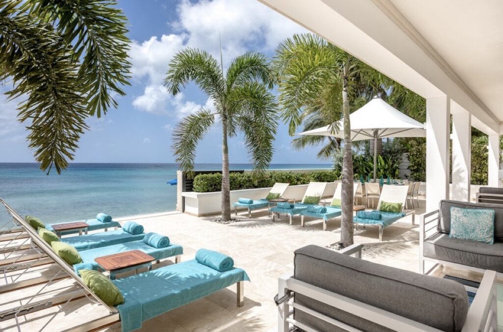 Luxury beachfront Villa terrace with lounge chairs overlooking turquoise ocean and palm trees