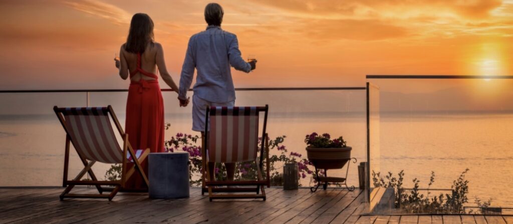 Couple relaxing on a luxury villa terrace at sunset overlooking the ocean