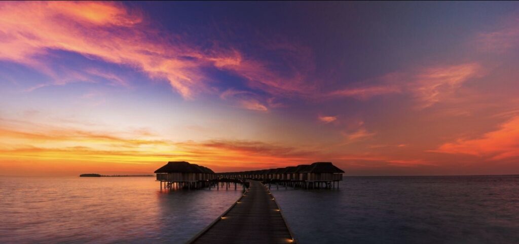 Luxury overwater villa in the Maldives at sunset with turquoise lagoon