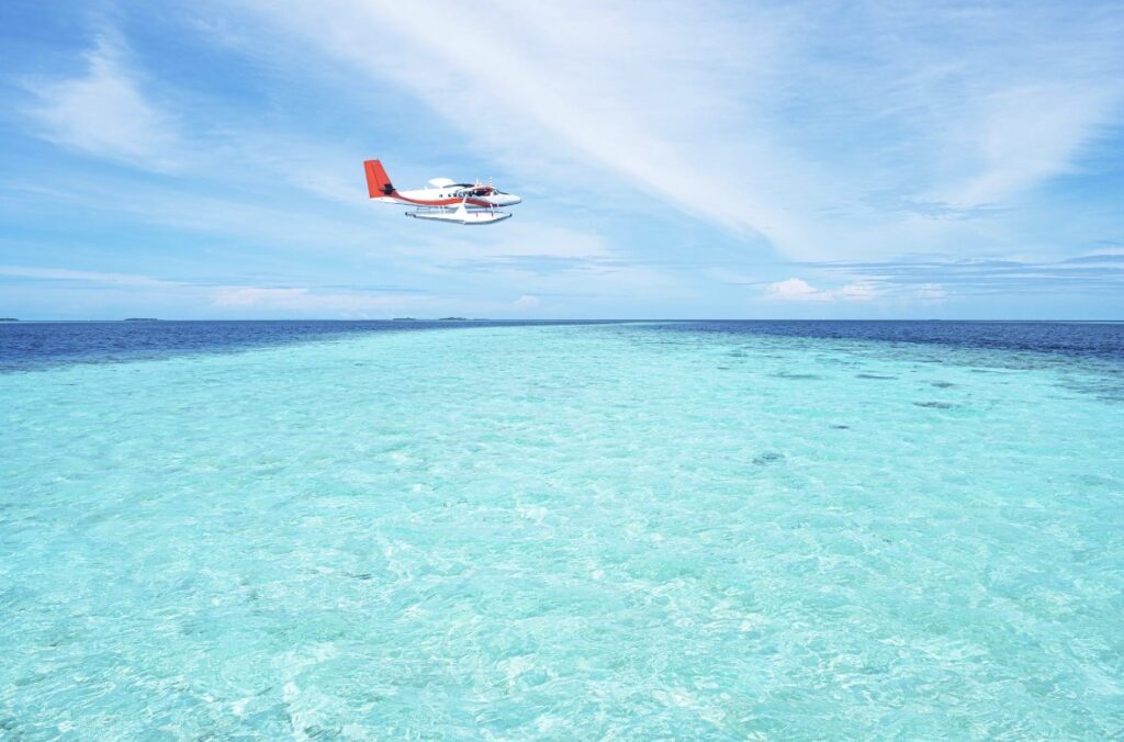 Maldives seaplane landing in turquoise lagoon near private island resort