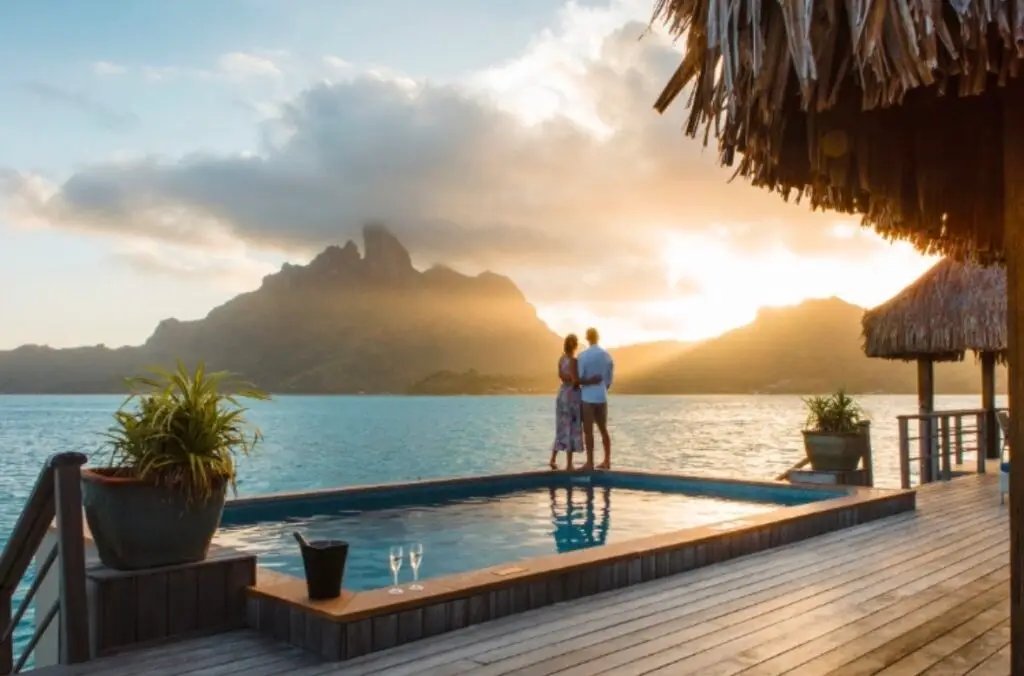 Couple enjoying private luxury overwater villa in Bora Bora with infinity pool and Mount Otemanu lagoon view