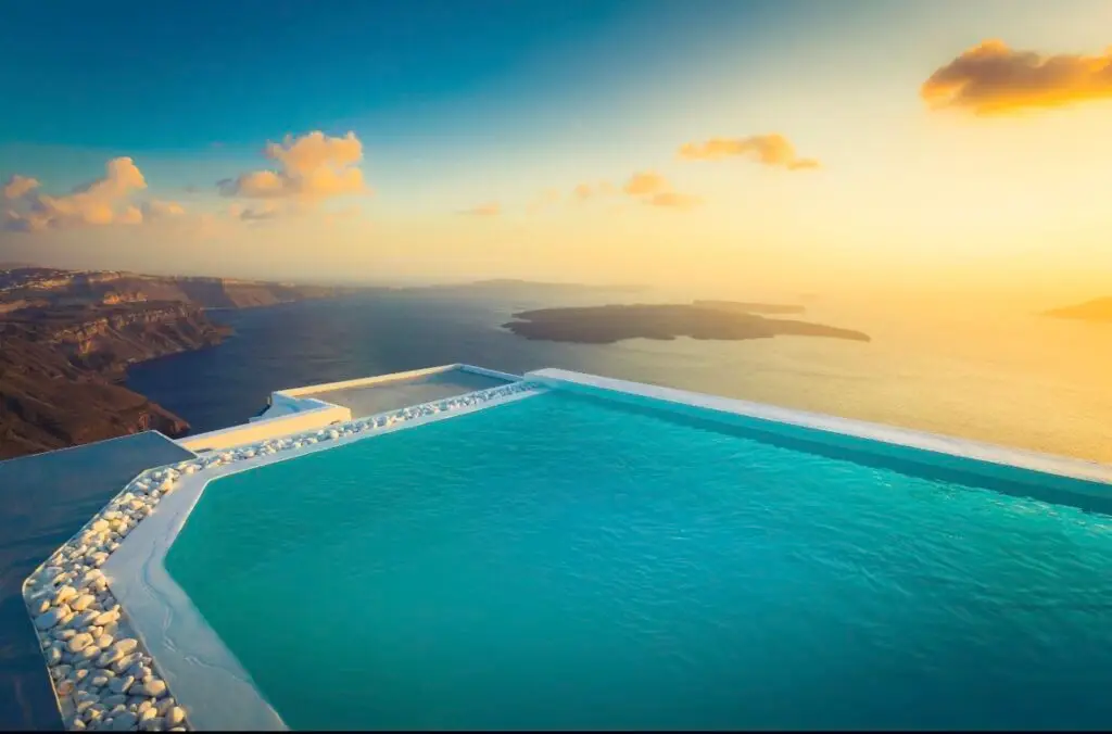 Luxury Santorini villa with infinity pool overlooking the caldera at sunset.