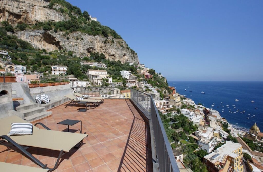 Luxury Amalfi Coast terrace view overlooking Positano cliffs and Mediterranean Sea.